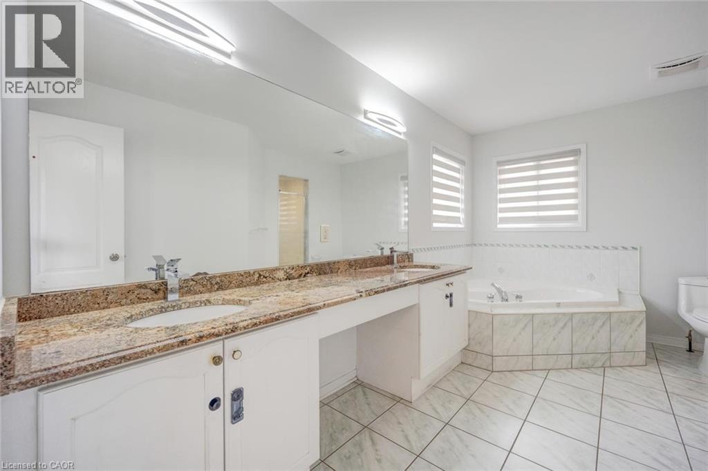 Spacious bathroom featuring a double vanity with stone-finish countertops, dual integrated sinks, and polished chrome faucets - 5 Freshspring Drive, Brampton, ON - Indoor Photo Showing Bathroom