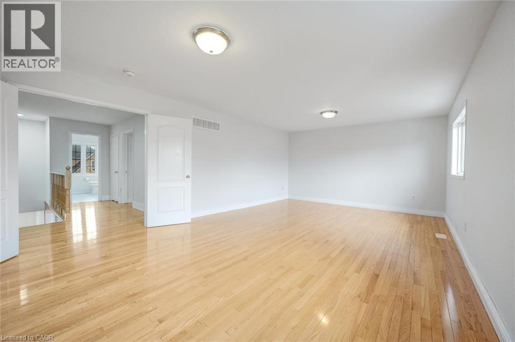 Spacious room featuring wood-finish flooring, white walls, and two flush-mount ceiling lights - 5 Freshspring Drive, Brampton, ON - Indoor Photo Showing Other Room