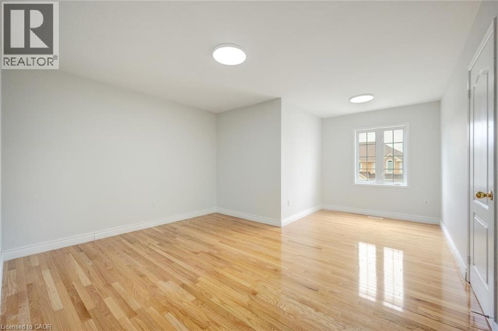 Bright interior room featuring wood-finish flooring, white baseboards, and white walls - 5 Freshspring Drive, Brampton, ON - Indoor Photo Showing Other Room