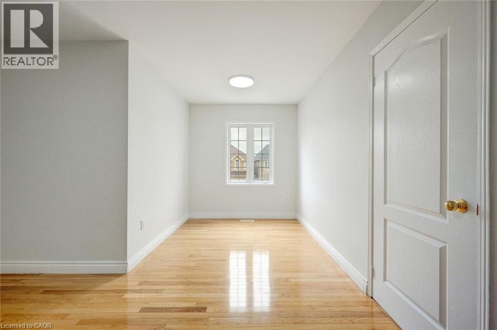 Bright interior space featuring wood-finish flooring, white walls, a single window, a flush mount ceiling light, and a paneled door - 5 Freshspring Drive, Brampton, ON - Indoor Photo Showing Other Room