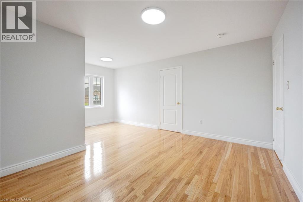 Spacious room featuring wood-finish flooring, white walls, multiple light fixtures, and a grid-paned window - 5 Freshspring Drive, Brampton, ON - Indoor Photo Showing Other Room