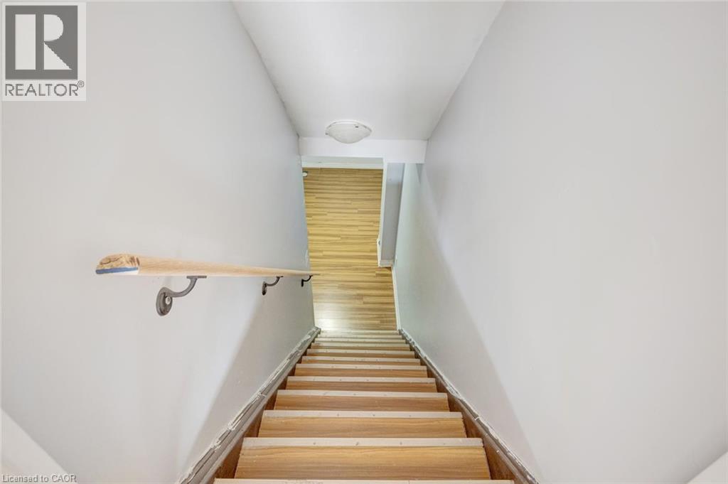 Stairwell featuring light wood-finish treads and risers, a light-toned wooden handrail with dark metal brackets, and white painted walls - 5 Freshspring Drive, Brampton, ON - Indoor Photo Showing Other Room
