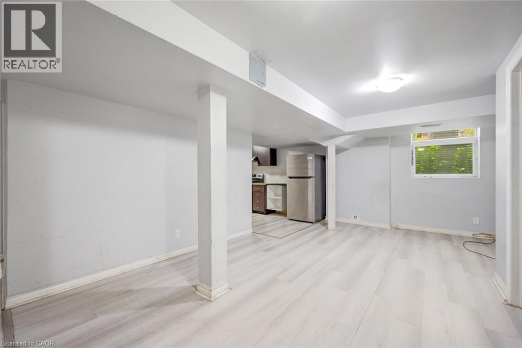 Spacious lower-level room featuring light wood-finish flooring, recessed lighting, and a kitchen area with stainless steel appliances - 5 Freshspring Drive, Brampton, ON - Indoor