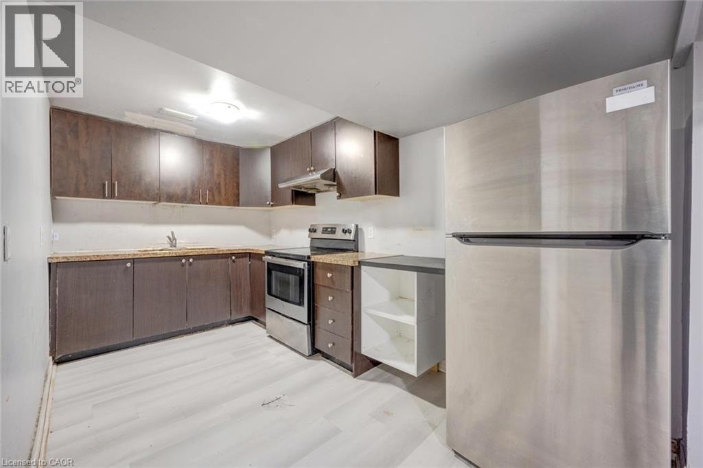 Compact kitchen featuring wood-finish cabinetry, light-toned countertops, and light wood-finish flooring - 5 Freshspring Drive, Brampton, ON - Indoor Photo Showing Kitchen
