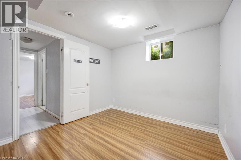 Room featuring wood-finish flooring, white baseboards, a white interior door, a light fixture, and a window - 5 Freshspring Drive, Brampton, ON - Indoor Photo Showing Other Room