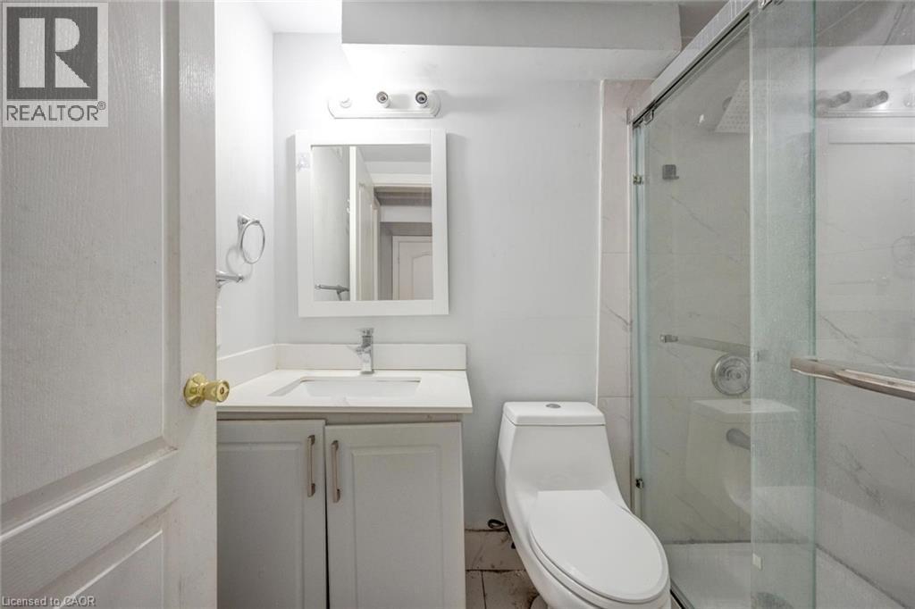 Bathroom featuring a white vanity with an undermount sink, a framed mirror, a modern toilet, and a glass-enclosed shower with tiled walls - 5 Freshspring Drive, Brampton, ON - Indoor Photo Showing Bathroom