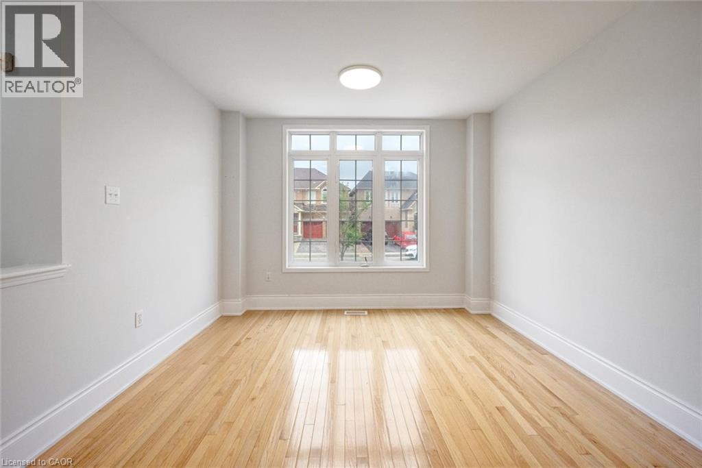 Bright interior space featuring light wood-finish flooring, white baseboards, and a prominent multi-pane window - 5 Freshspring Drive, Brampton, ON - Indoor Photo Showing Other Room