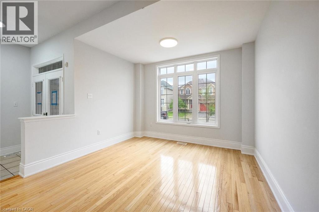 Hardwood flooring throughout a room featuring a multi-pane window, white trim, and a contemporary ceiling light fixture - 5 Freshspring Drive, Brampton, ON - Indoor Photo Showing Other Room