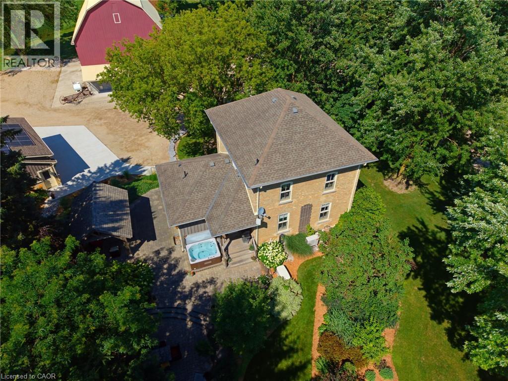 Aerial perspective showcasing a brick residence with a gabled roof and surrounding mature trees - 8430 Road 146, Listowel, ON - Outdoor