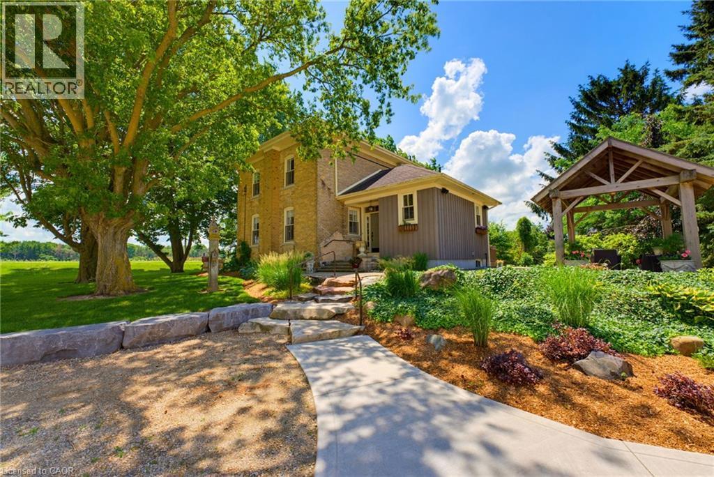 Stone facade residence featuring a covered entry porch and a concrete pathway - 8430 Road 146, Listowel, ON - Outdoor