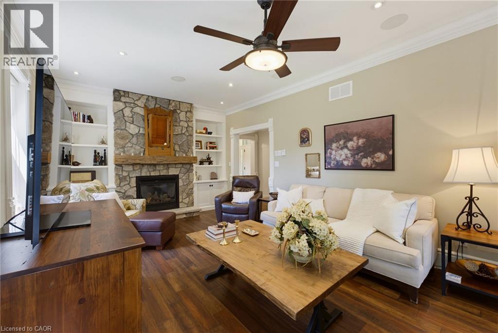 Spacious living area featuring stone-clad fireplace, built-in shelving, wood-finish flooring, crown molding, and recessed lighting - 8430 Road 146, Listowel, ON - Indoor Photo Showing Living Room With Fireplace