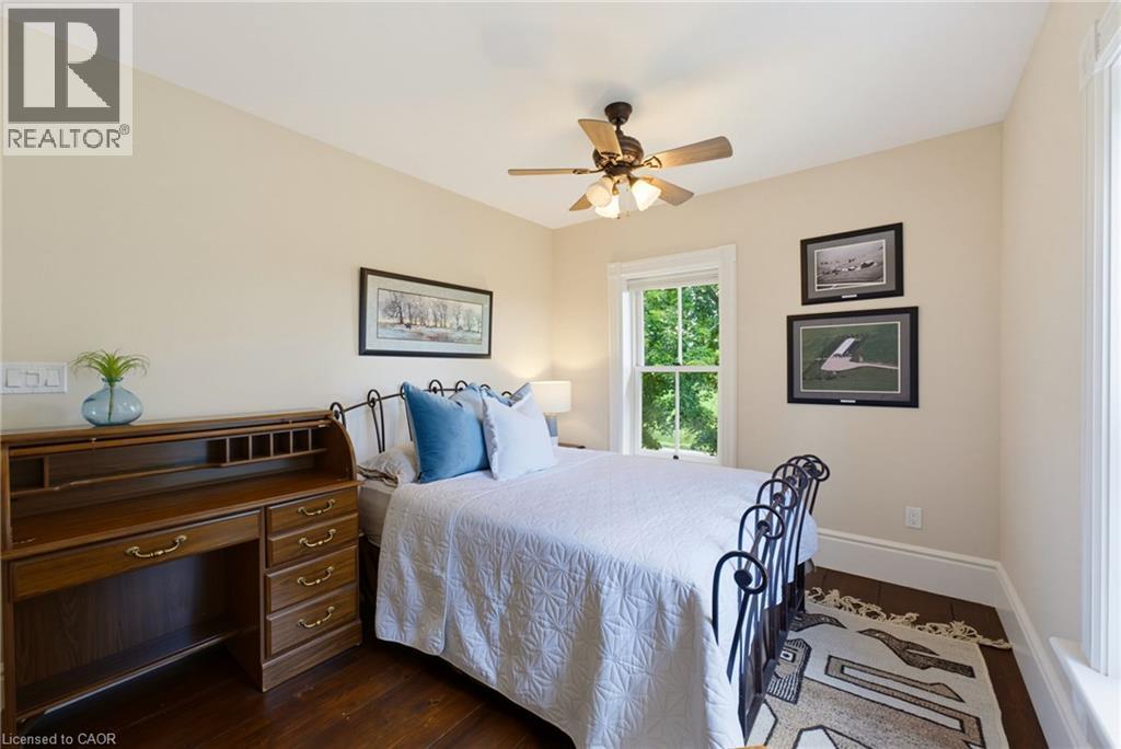 Bedroom featuring rich wood-finish flooring, a ceiling fan with integrated lighting, a double-hung window, and neutral wall tones - 8430 Road 146, Listowel, ON - Indoor Photo Showing Bedroom