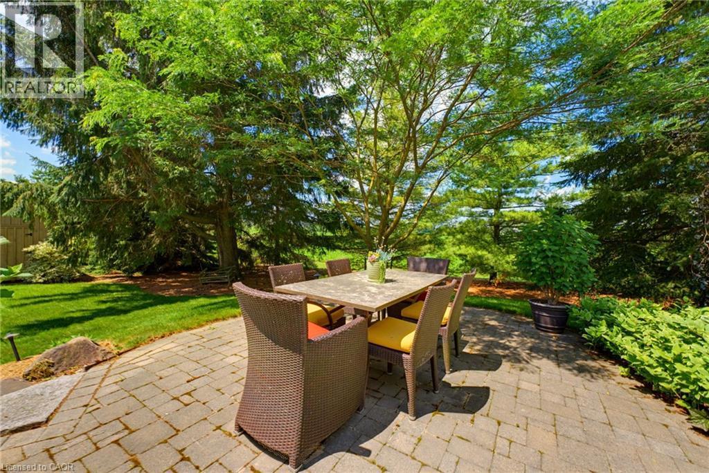 Paver patio surrounded by lush landscaping and mature trees - 8430 Road 146, Listowel, ON - Outdoor