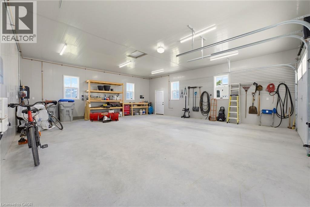 Spacious garage featuring a concrete floor, multiple windows, a rear access door, track lighting, and overhead garage door rails - 8430 Road 146, Listowel, ON - Indoor Photo Showing Garage