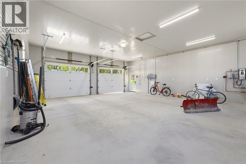 Spacious two-bay garage featuring bright overhead lighting, a utility door, and a built-in wall organization system - 8430 Road 146, Listowel, ON - Indoor Photo Showing Garage