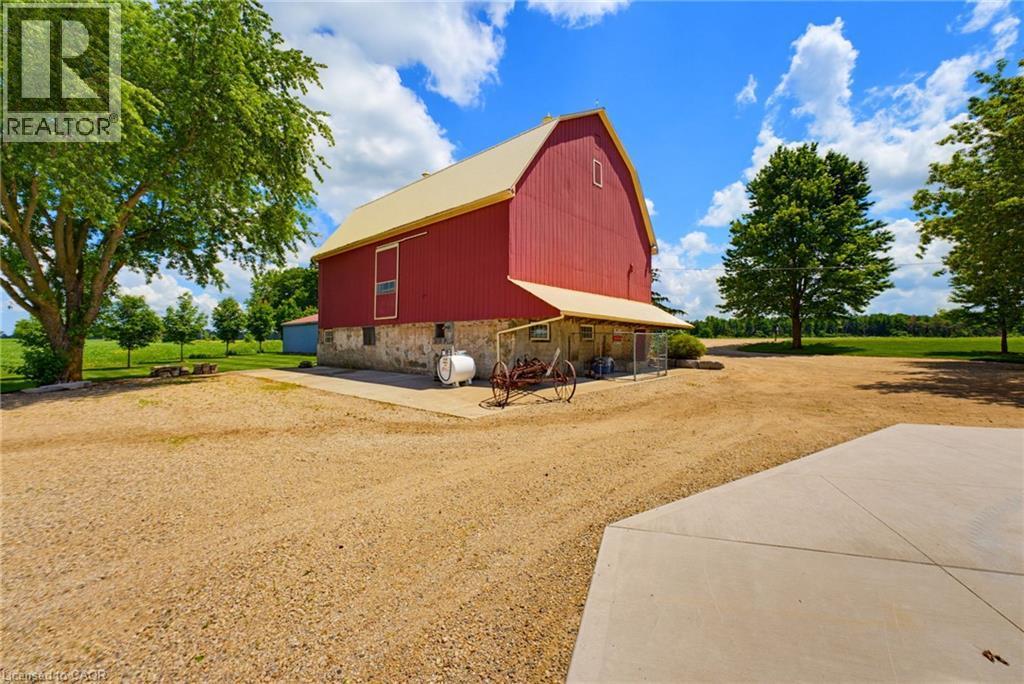 Classic red barn structure featuring a stone foundation and a light-colored roof - 8430 Road 146, Listowel, ON - Outdoor