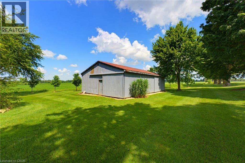 Detached barn structure with a red roof, gray siding, and a sliding entry door - 8430 Road 146, Listowel, ON - Outdoor