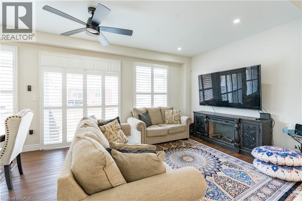 Spacious living area featuring wood-finish flooring, white plantation shutters, an integrated fireplace unit, recessed lighting, and a ceiling fan - 122 Iron Gate Street, Kitchener, ON - Indoor Photo Showing Living Room With Fireplace