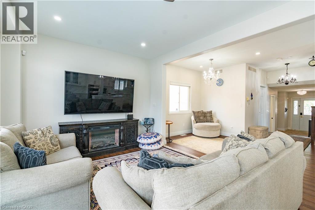 Spacious living area featuring wood-finish flooring, recessed lighting, and a decorative fireplace unit - 122 Iron Gate Street, Kitchener, ON - Indoor Photo Showing Living Room With Fireplace