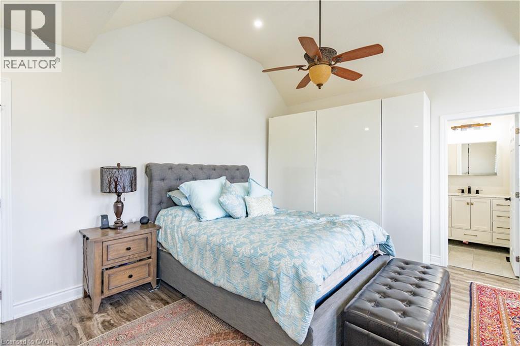 Vaulted ceiling bedroom featuring wood-finish flooring, built-in glossy white wardrobes, and a ceiling fan - 122 Iron Gate Street, Kitchener, ON - Indoor Photo Showing Bedroom