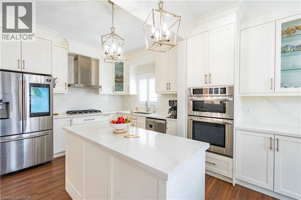Bright kitchen featuring white cabinetry, a center island with a white countertop, stainless steel appliances, and wood-finish flooring - 122 Iron Gate Street, Kitchener, ON - Indoor Photo Showing Kitchen With Stainless Steel Kitchen With Upgraded Kitchen
