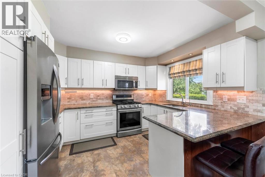 Kitchen featuring white shaker cabinetry, stainless steel appliances, and a tiled backsplash - 1063 Joan Drive, Burlington, ON - Indoor Photo Showing Kitchen With Stainless Steel Kitchen With Upgraded Kitchen