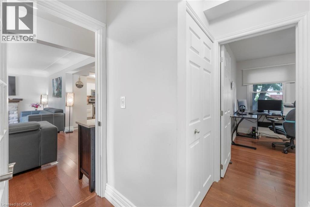 Hallway featuring wood-finish flooring, white paneled doors, and bright white walls - 1063 Joan Drive, Burlington, ON - Indoor Photo Showing Other Room