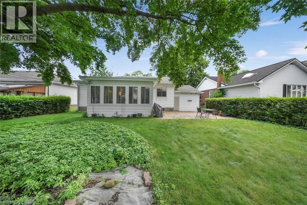 Expansive backyard featuring a large green lawn, mature trees, and a sunroom extension - 1063 Joan Drive, Burlington, ON - Outdoor