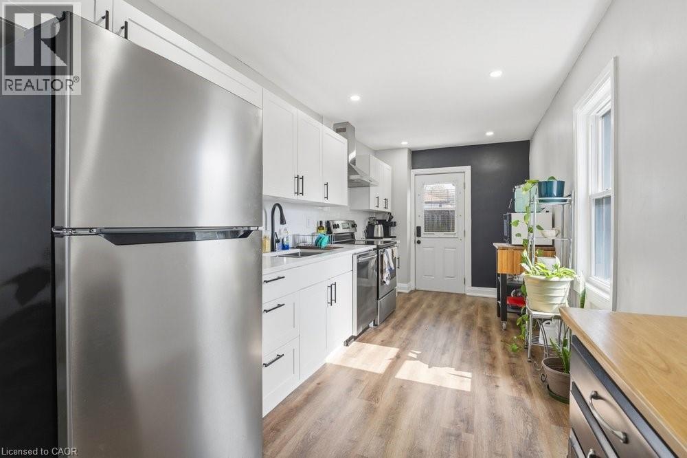 Contemporary kitchen featuring stainless steel appliances, white cabinetry with matte black hardware, wood-finish flooring, and recessed lighting - 773 Lawrence Road, Hamilton, ON - Indoor Photo Showing Kitchen