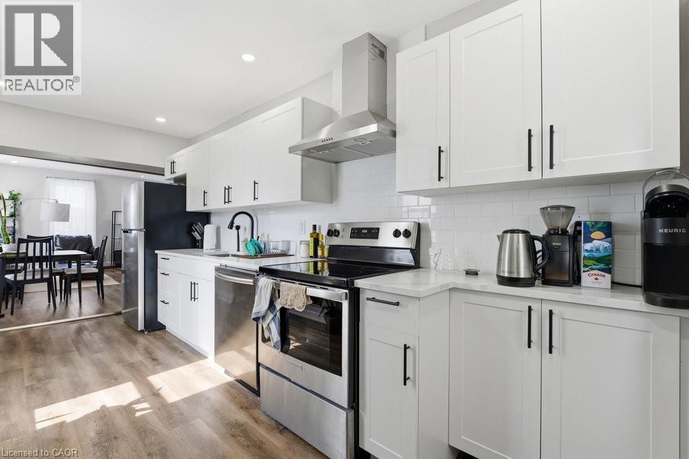 Contemporary kitchen featuring white shaker cabinetry, stainless steel appliances, a subway tile backsplash, and light-tone wood-finish flooring - 773 Lawrence Road, Hamilton, ON - Indoor Photo Showing Kitchen With Upgraded Kitchen