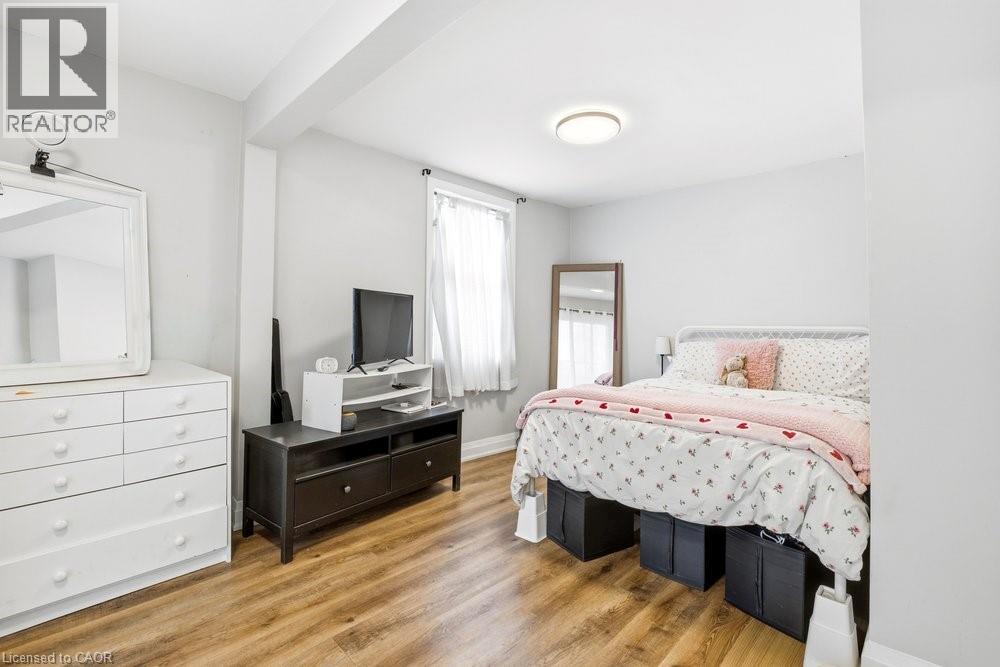Bedroom featuring wood-finish flooring, a window with natural light, and a ceiling-mounted light fixture - 773 Lawrence Road, Hamilton, ON - Indoor Photo Showing Bedroom
