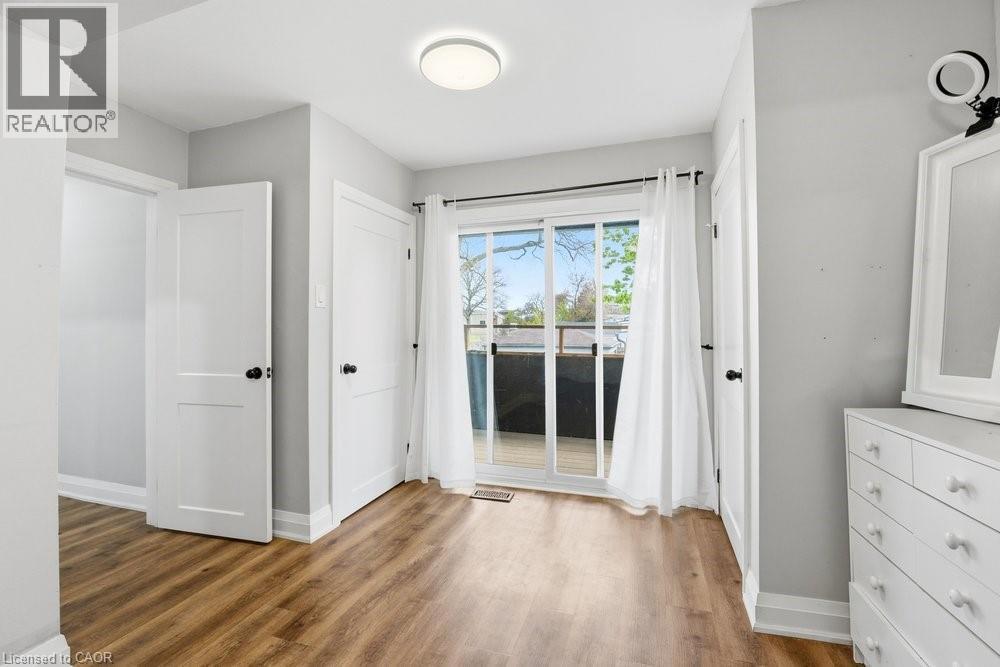 Wood-finish flooring throughout, featuring a sliding glass door providing natural light and access to a deck with dark railing - 773 Lawrence Road, Hamilton, ON - Indoor Photo Showing Other Room