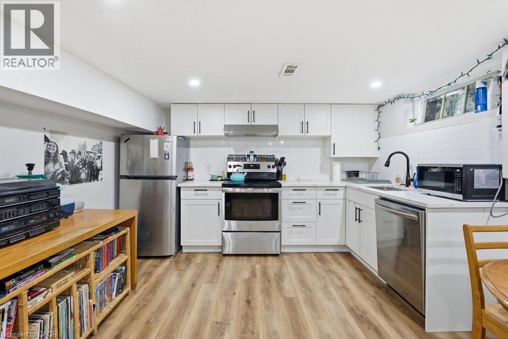 Modern kitchen featuring white cabinetry, stainless steel appliances, wood-finish flooring, white subway tile backsplash, and recessed lighting - 773 Lawrence Road, Hamilton, ON - Indoor Photo Showing Kitchen