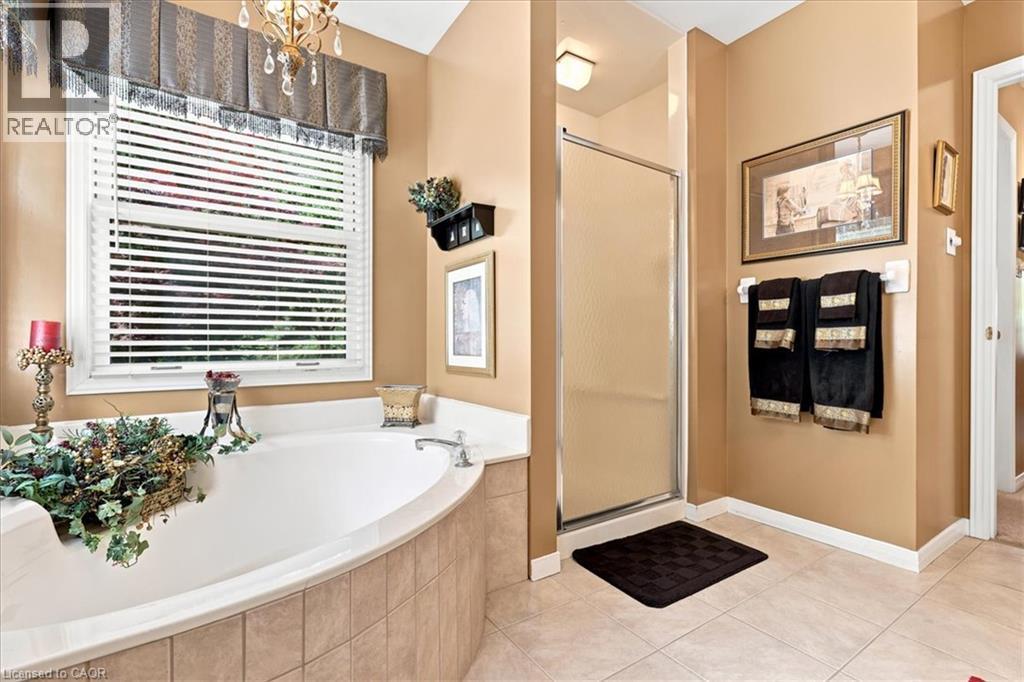 Soaking tub with a tiled surround, framed window with blinds, and an overhead valance - 39 Everwood Run, Kitchener, ON - Indoor Photo Showing Bathroom