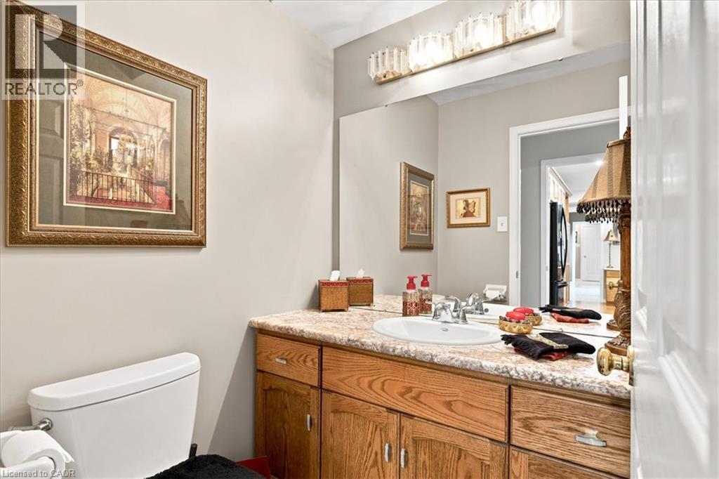 Bathroom featuring a vanity with a light-colored countertop, an undermount sink, and wood-finish cabinetry - 39 Everwood Run, Kitchener, ON - Indoor Photo Showing Bathroom