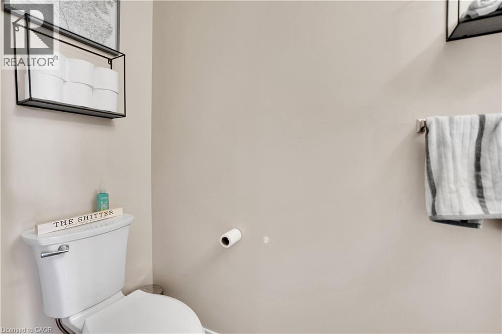 White toilet with polished chrome flush handle, light-toned wall paint, and a wall-mounted towel bar - 60 Featherstone Street, Kitchener, ON - Indoor Photo Showing Bathroom