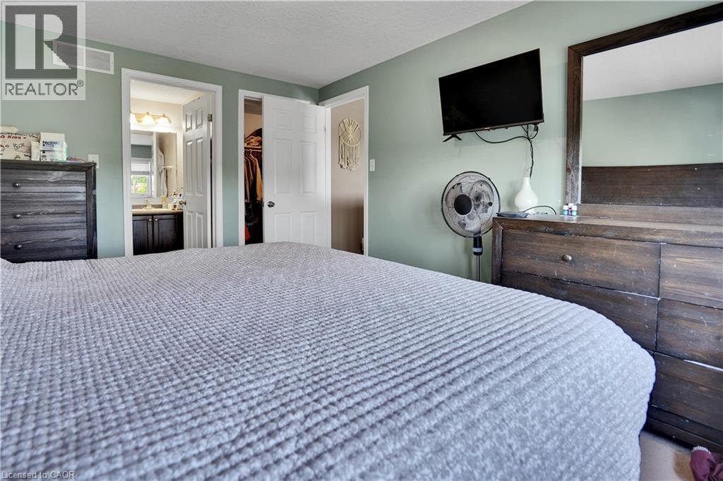 Bedroom featuring light green walls, white trim, and direct access to a bathroom with a vanity and mirror - 60 Featherstone Street, Kitchener, ON - Indoor Photo Showing Bedroom