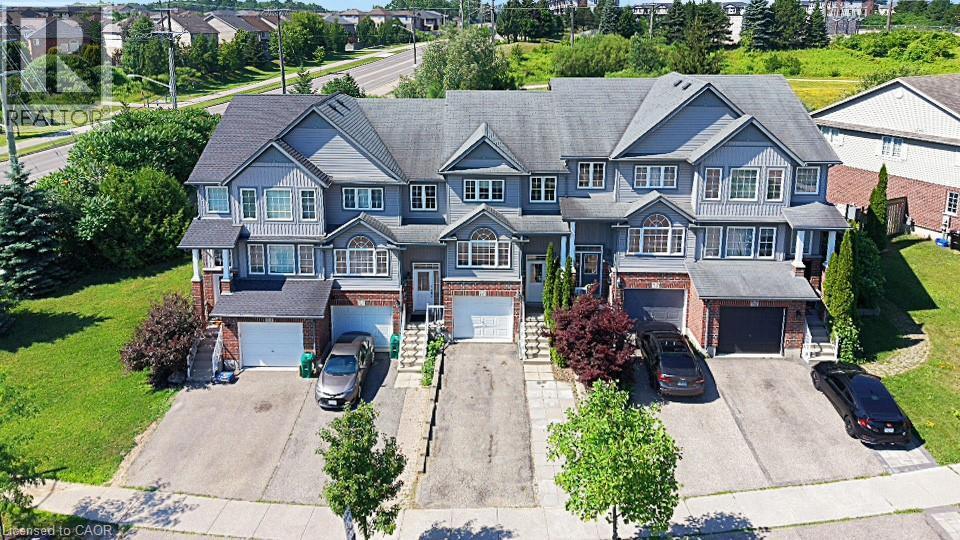 Townhome exterior featuring gray siding, brick accents, white trim, and a dark shingled roof - 60 Featherstone Street, Kitchener, ON - Outdoor With Facade