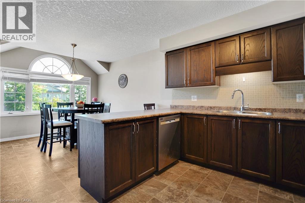 Kitchen featuring wood-finish cabinetry, stainless steel dishwasher, and a tile backsplash - 60 Featherstone Street, Kitchener, ON - Indoor Photo Showing Kitchen