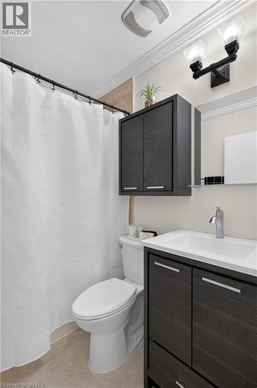 Bathroom featuring a wall-mounted vanity with a white countertop and integrated sink, contemporary dark wood-finish cabinetry, a chrome faucet, and a mirror - 236 Hammersmith Court, Burlington, ON - Indoor Photo Showing Bathroom