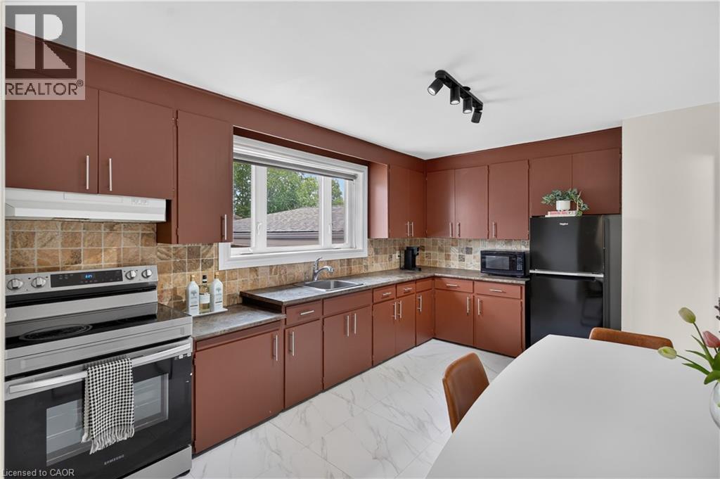 Kitchen with brown cabinetry, marble-look floor tiling, and a tiled backsplash - 236 Hammersmith Court, Burlington, ON - Indoor Photo Showing Kitchen
