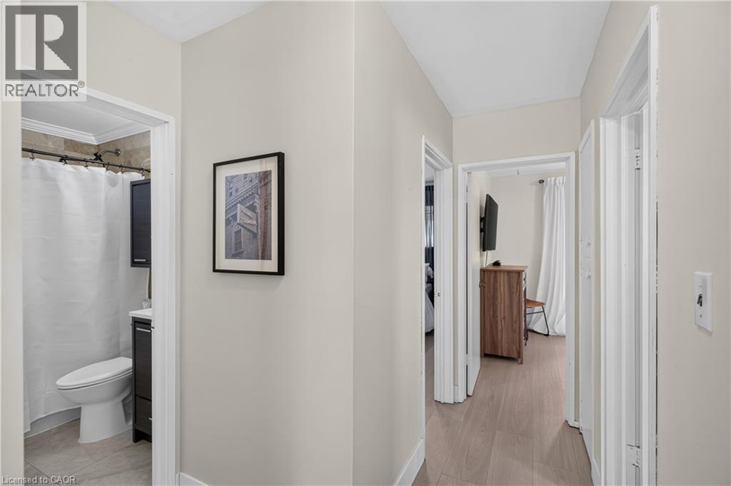 Neutral-toned hallway with light wood-finish flooring, featuring multiple doorways and white trim - 236 Hammersmith Court, Burlington, ON - Indoor Photo Showing Bathroom