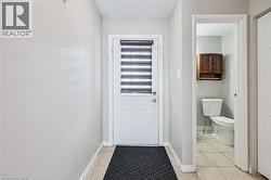 Entryway featuring a white door with integrated blinds, ceramic tile flooring, and light gray wall paint - 