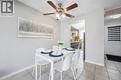 Dining area featuring tile flooring, a ceiling fan with integrated lighting, and an open entryway to the kitchen - 