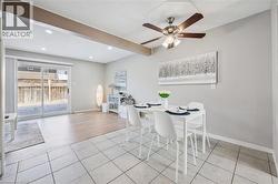 Dining area with neutral grey wall paint, square tile flooring, and a ceiling fan with integrated lighting - 