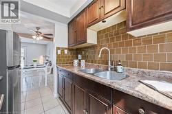 Kitchen featuring dark wood cabinetry, a double basin stainless steel sink with a pull-down faucet, and a brown subway tile backsplash - 