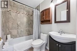 Full bathroom featuring a white bathtub, ceramic tile surround with decorative accent band, and a white toilet - 