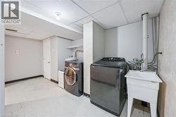 Dedicated laundry space featuring a utility sink, a drop-ceiling, and tiled flooring - 