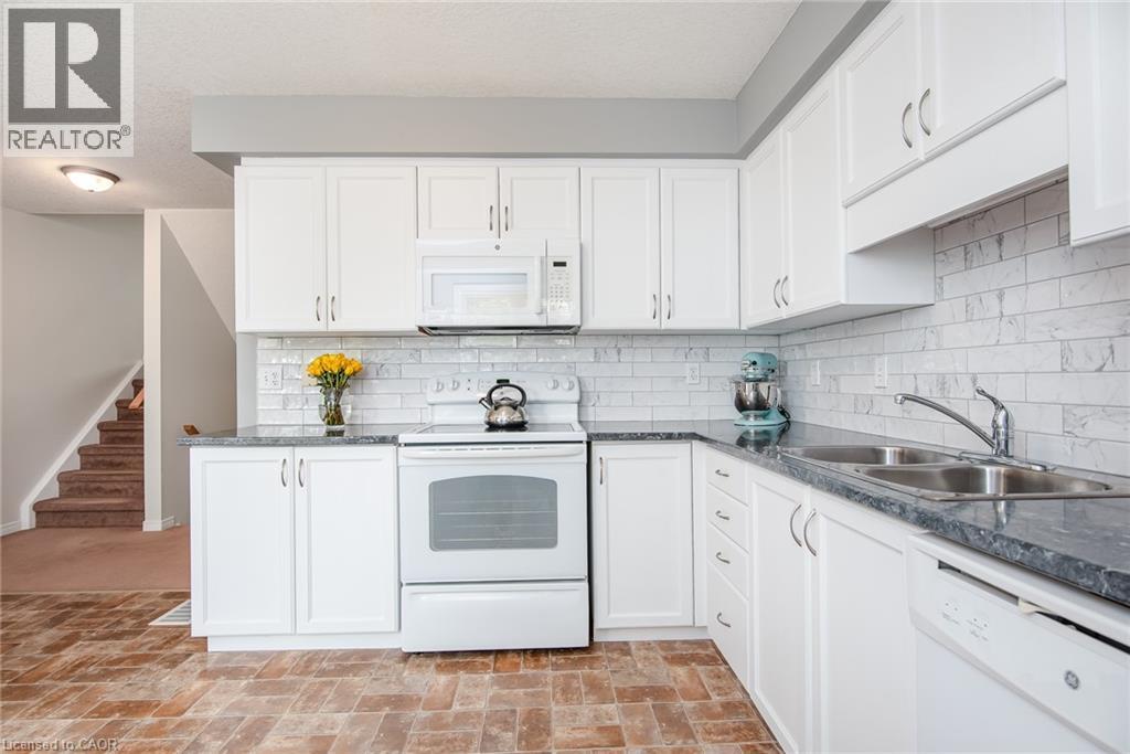 Kitchen featuring white cabinetry, grey countertops, white subway tile backsplash, and wood-finish flooring - 38 David Bergey Drive, Kitchener, ON - Indoor Photo Showing Kitchen With Double Sink
