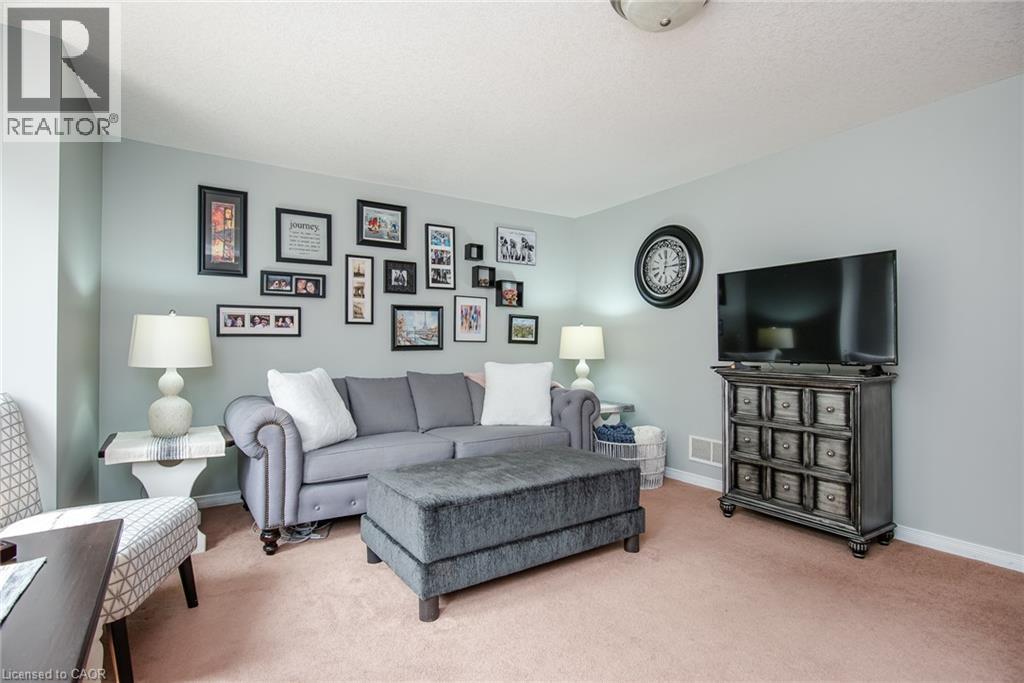 Carpeted living space with light blue-gray walls, a flush-mount ceiling light fixture, and white baseboards - 38 David Bergey Drive, Kitchener, ON - Indoor Photo Showing Living Room